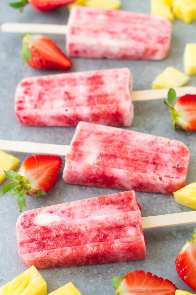 These Fruit and Yogurt Popsicles are easy to make and bursting with fresh fruit flavor! This homemade strawberry popsicle recipe is made with only four ingredients. These healthy popsicles are a fun summer treat for kids! Homemade strawberry, pineapple and yogurt popsicles with fresh fruit.