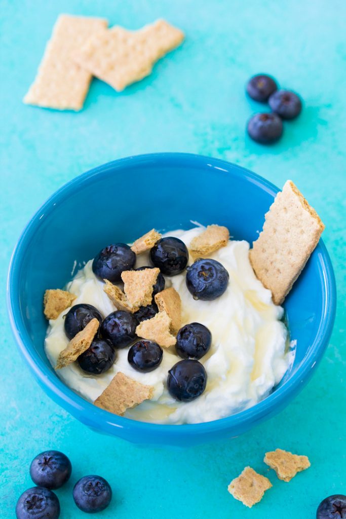 Greek yogurt bowl with blueberries and graham cracker.