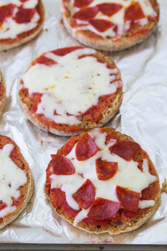 These English Muffin Pizzas are perfect for kids! These pizzas are made in the oven and they are almost the same as regular pizza, but easier! The best easy mini pizza recipe, with lots of ideas for toppings including pepperoni or healthy veggies. Perfect for kids lunches, snacks or dinner! Cheese and pepperoni English muffin mini pizzas.