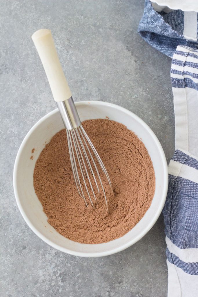 An easy chocolate mug cake that tastes like a brownie in a cup. This chocolate cake in a mug is a delicious microwave dessert that even a kid can make! This recipe has no egg and cooks in just 1 minute! Whisking dry ingredients in a bowl for a chocolate mug cake.